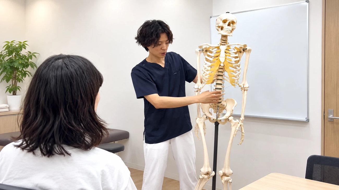 骨の模型を使って身体の状態を説明する院長