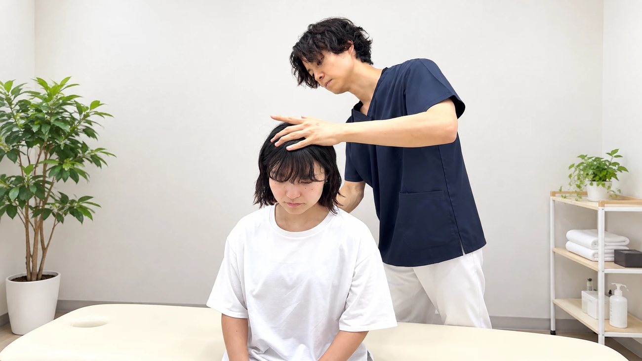 頭にやさしく手を当てる院長の施術
